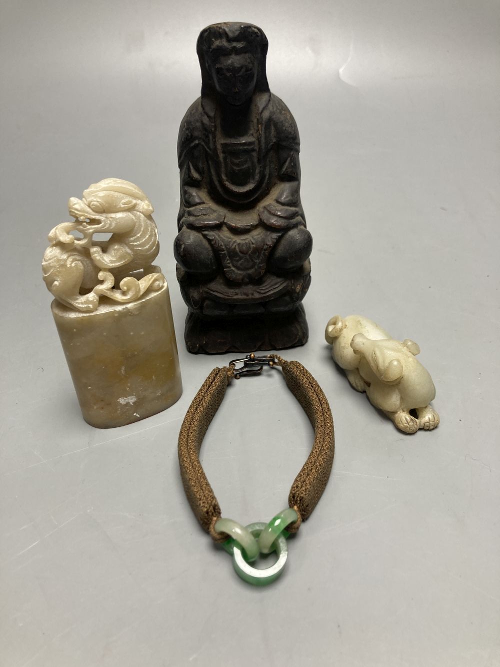 A group of Chinese Works of Art, jades, soapstones, a wooden Buddha and a jade and hair bracelet, tallest 14cm